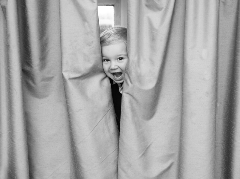 Boy hiding behind curtains